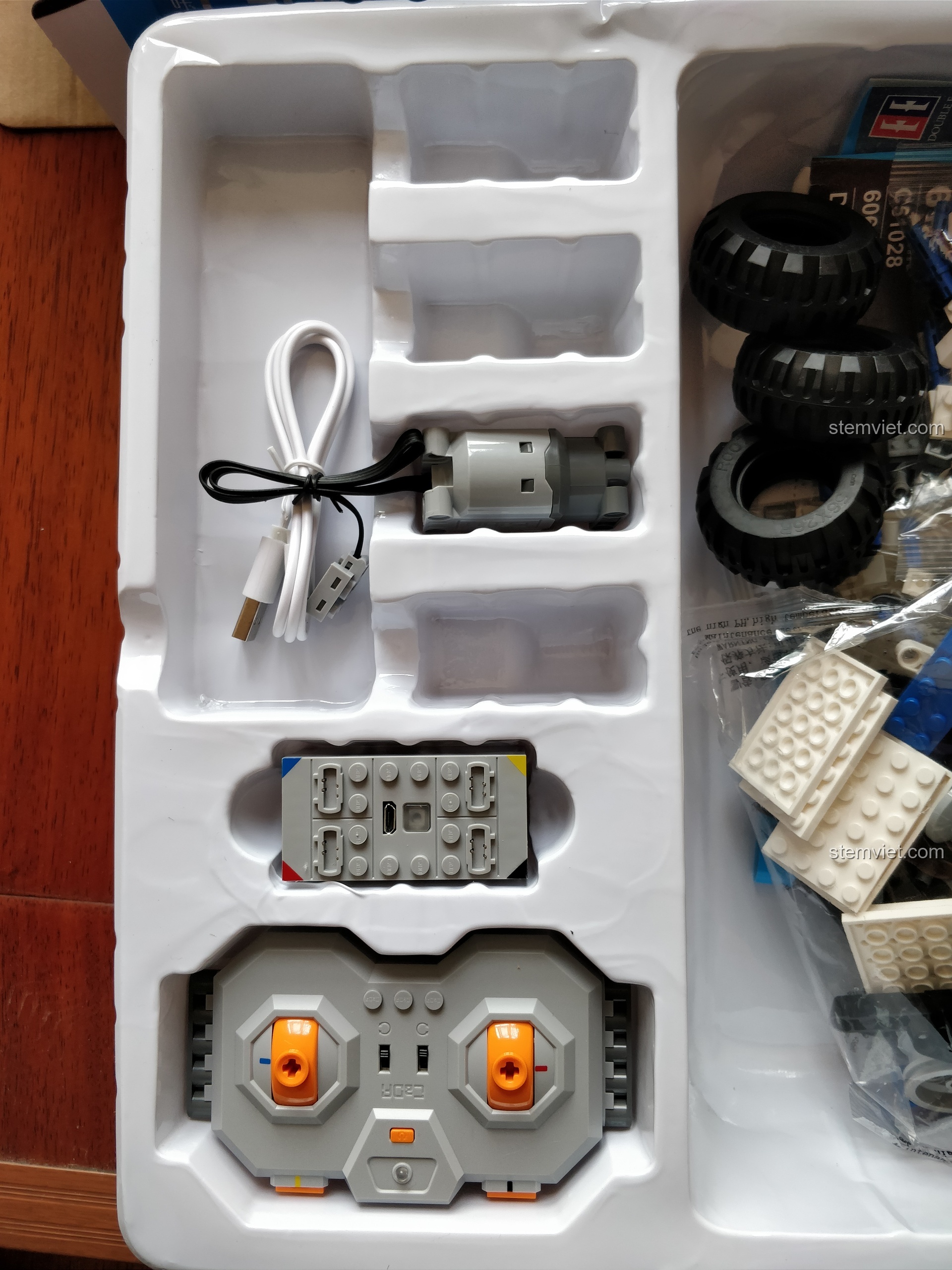 Cận cảnh các linh kiện điện tử trong bộ Robot DADA C51028: điều khiển, pin, động cơ và cáp sạc.