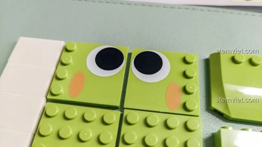 Cận cảnh các mảnh ghép in hình mắt và má hồng của Khủng long T-Rex trong bộ JAKI JK5102, chi tiết sắc nét.