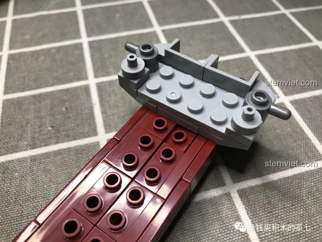 Mảnh ghép màu xám đang được đặt lên phần thân tàu sân bay Liêu Ninh, tạo thành lớp giữa của mô hình.