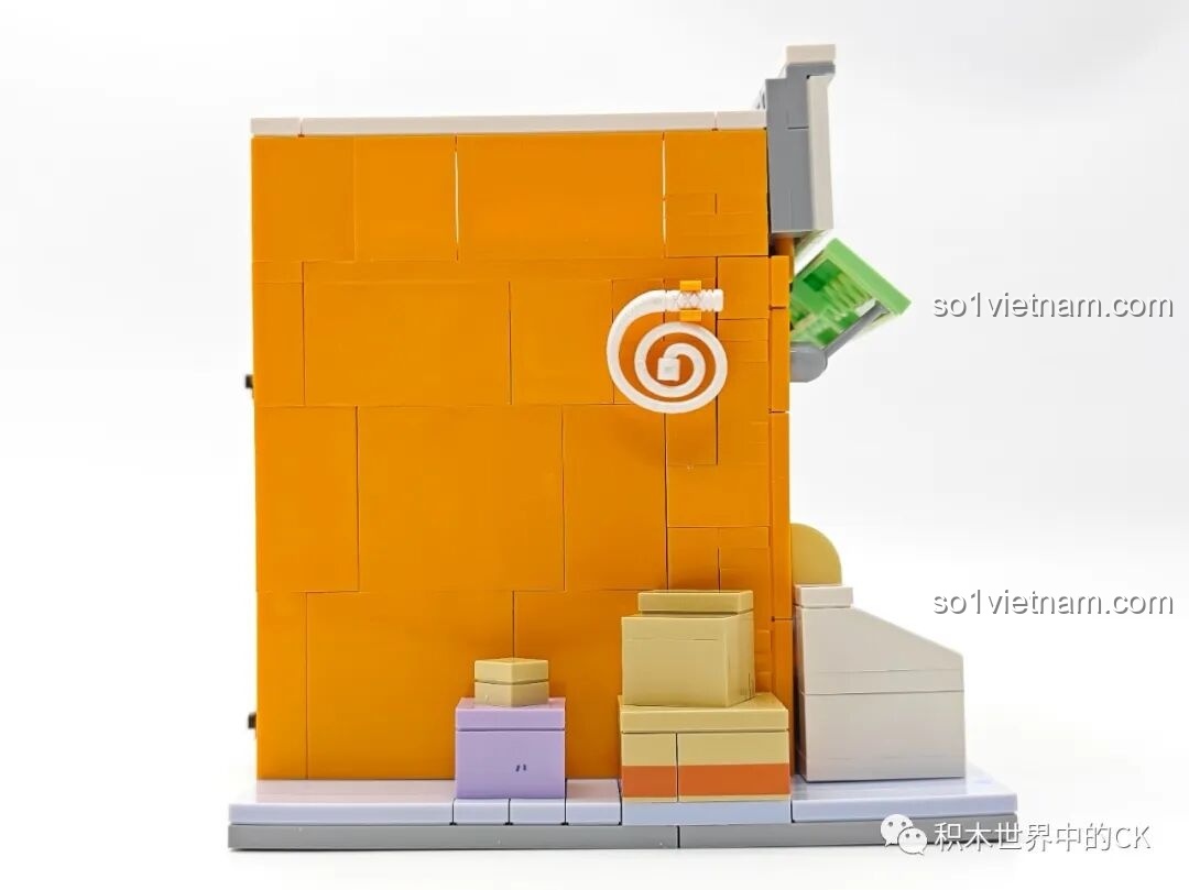 Mặt bên trái của mô hình Tiệm Tạp Hóa Maruko, với các thùng hàng và một cuộn dây trang trí trên tường.