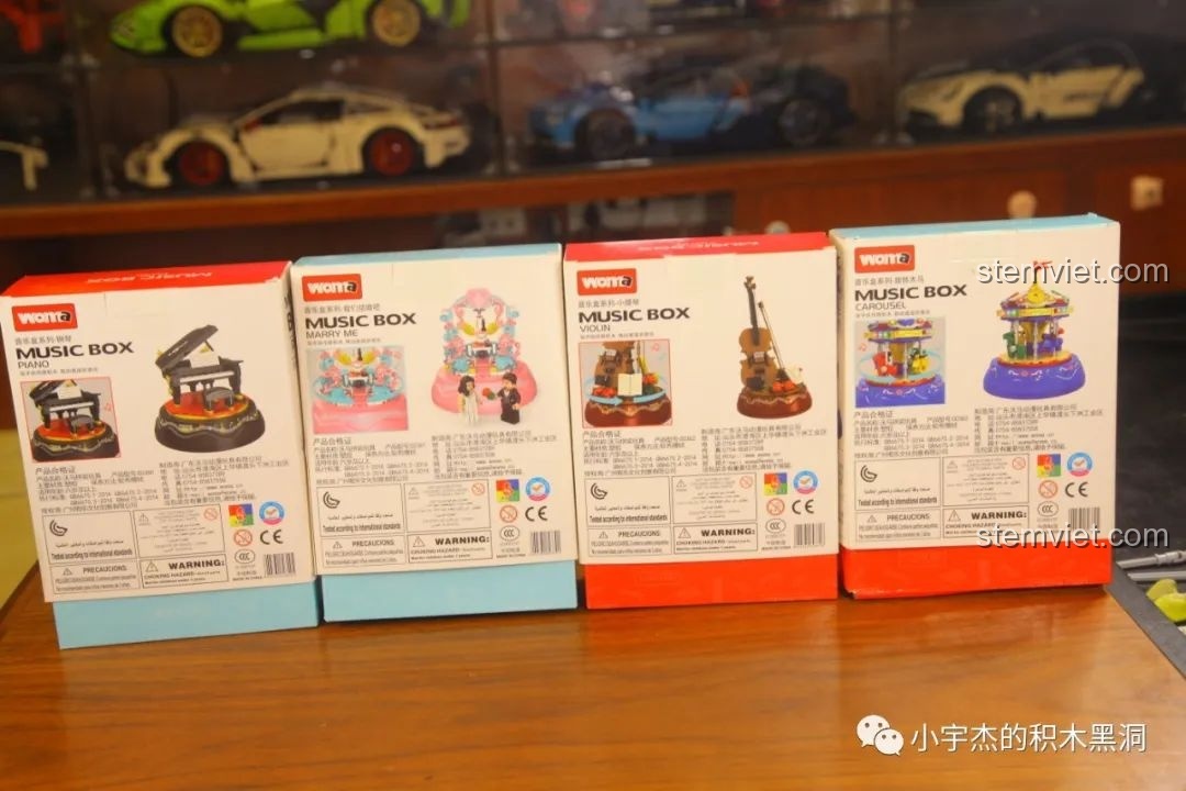 Mặt sau của bốn hộp đồ chơi lắp ráp WOMA Music Box, hiển thị thông tin chi tiết và mã vạch của từng sản phẩm.