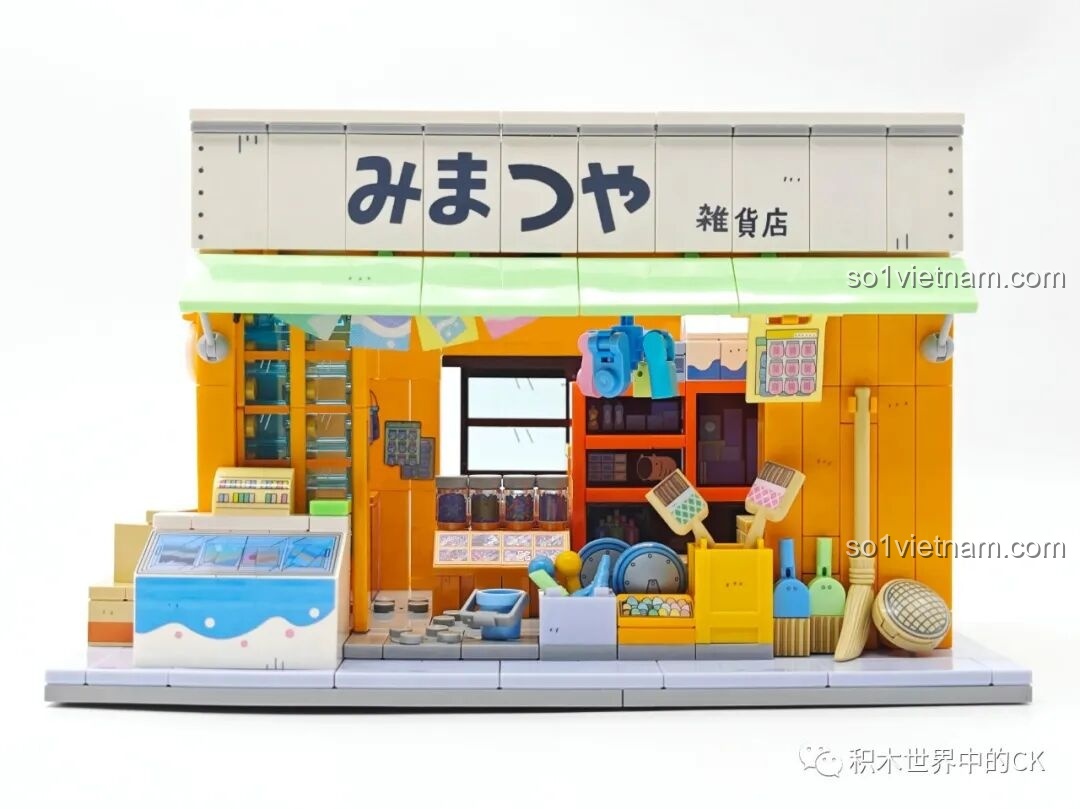 Mặt trước của mô hình Tiệm Tạp Hóa Maruko Wekki, với biển hiệu, mái hiên và các sạp hàng đầy màu sắc.