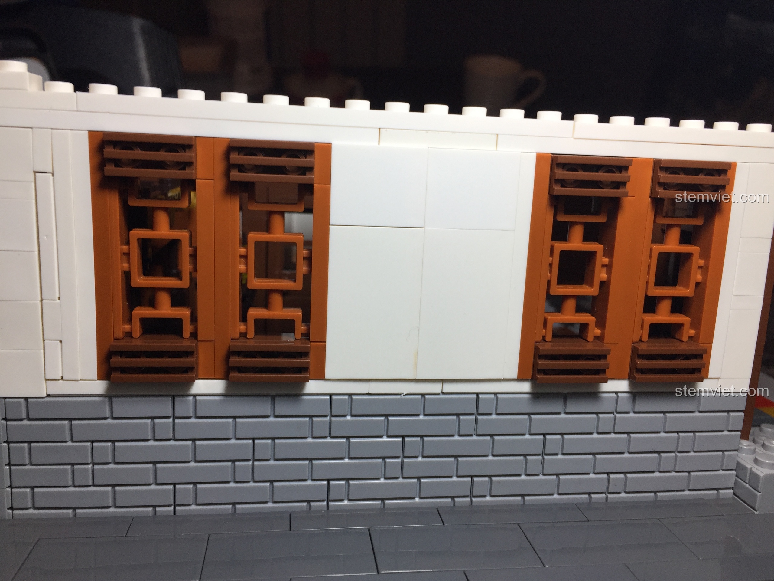 Mặt tường bên hông của Vạn Phúc Khách Sạn với tường trắng và các cửa sổ hoa văn màu nâu.