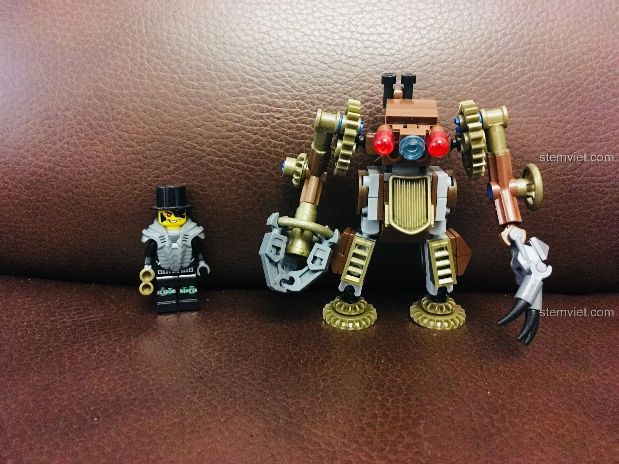 Mô hình mech nhỏ gọn của Kaizhi với bánh răng màu đồng nổi bật, đứng cạnh một minifigure, thể hiện sự tinh xảo.
