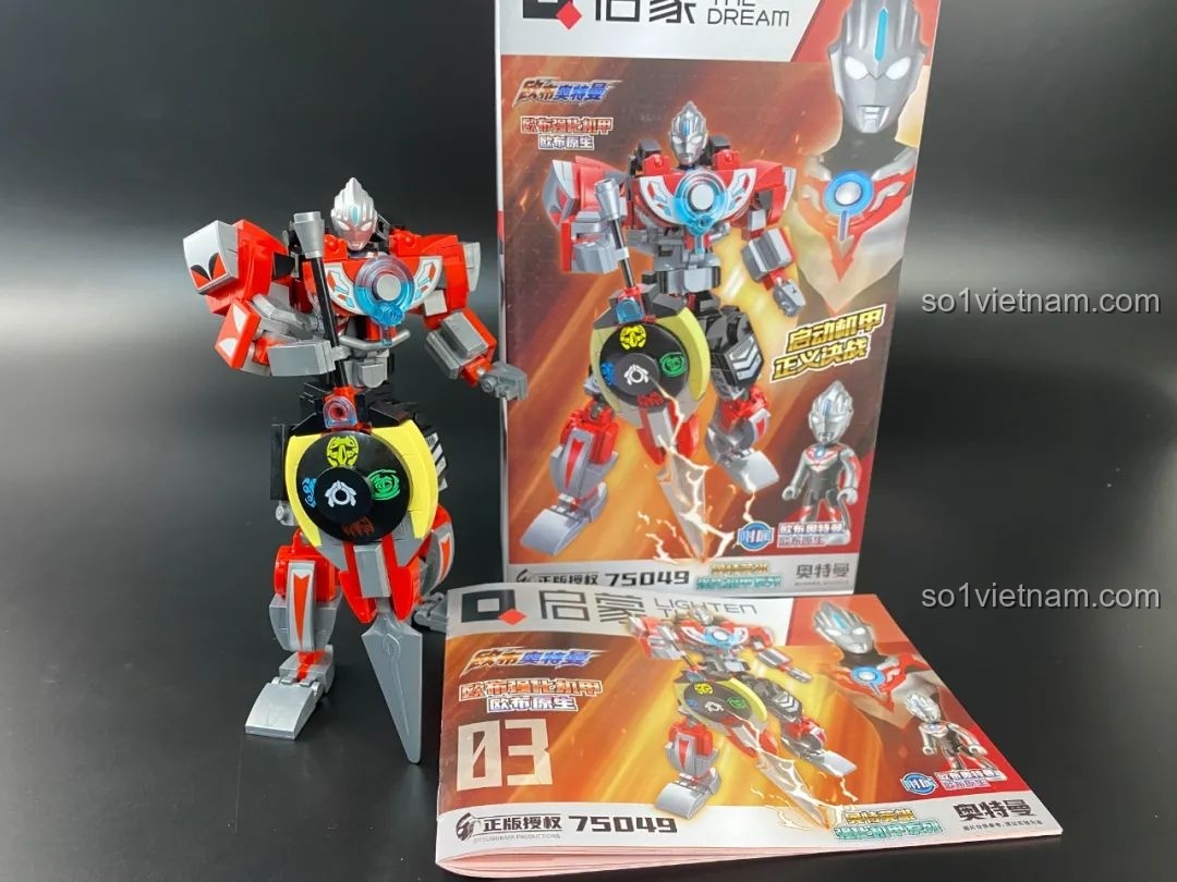 Mô hình Mecha Orb Origin Qman 75049 đã hoàn thiện, đứng bên cạnh hộp và sách hướng dẫn.