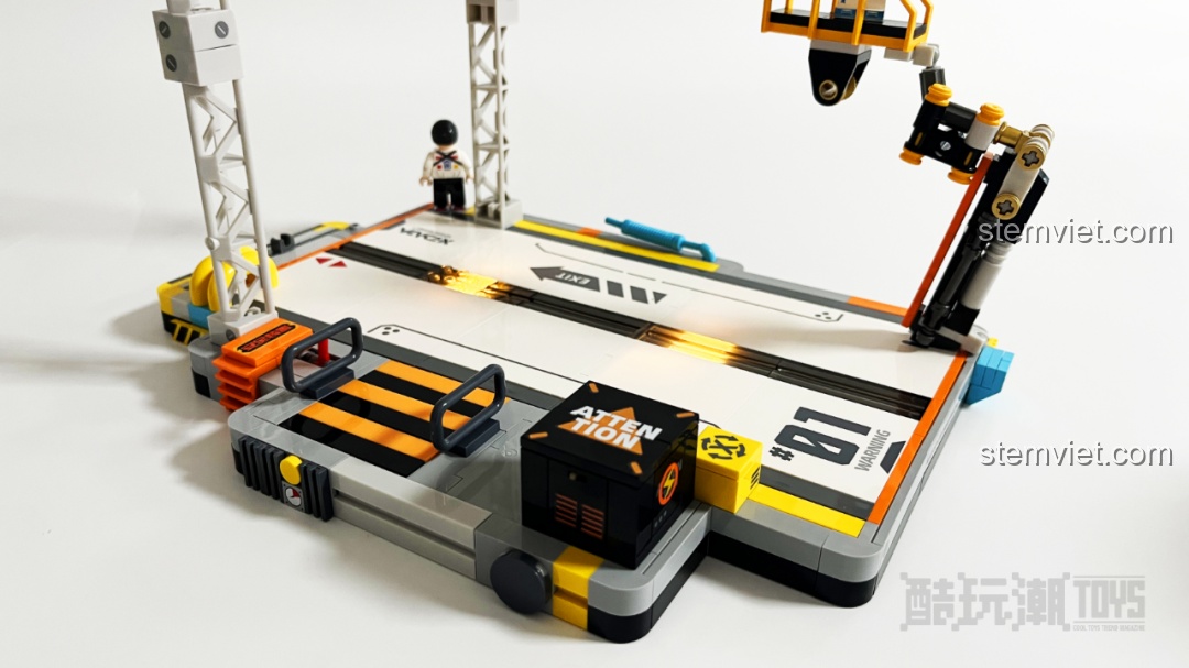 Cận cảnh minifigure Kỹ sư trưởng với mái tóc xanh và trang phục phi hành gia đang đứng trên cánh tay robot.