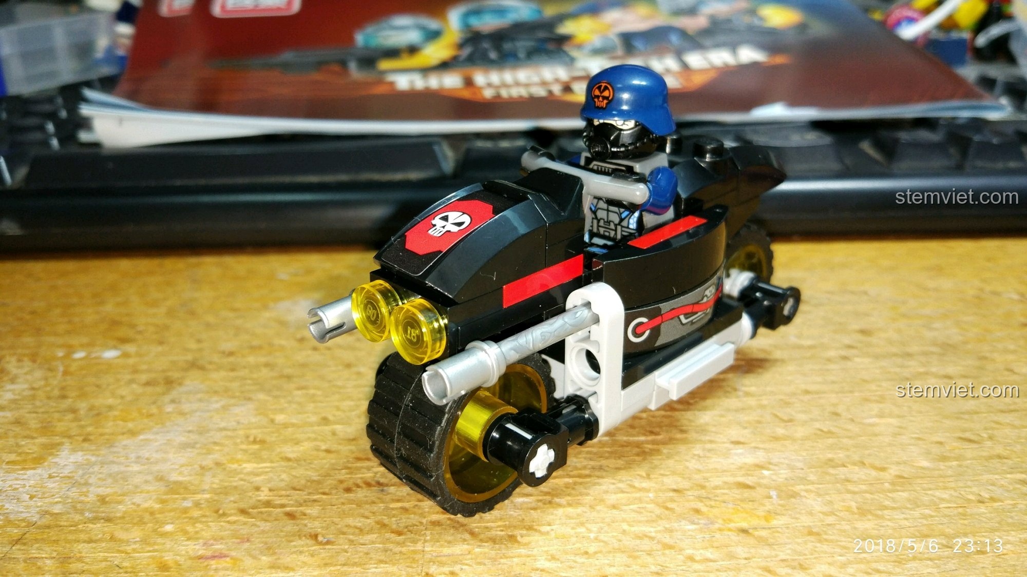 Minifigure lính phản diện QMAN đang ngồi lái chiếc mô tô mini, thể hiện khả năng tương tác của mô hình.