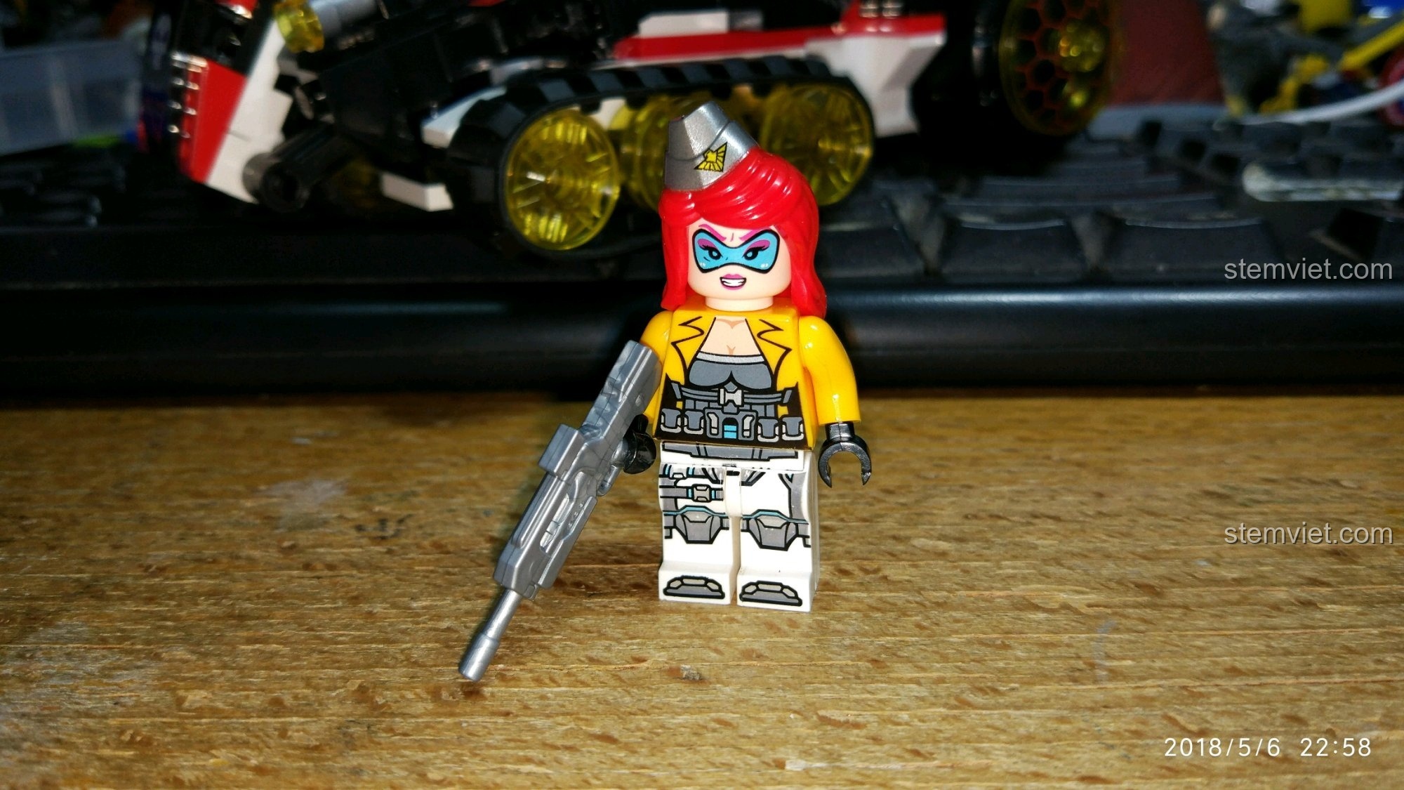Minifigure nữ chiến binh tóc đỏ trong bộ QMAN 2715, mặc trang phục chiến đấu và cầm súng bạc.
