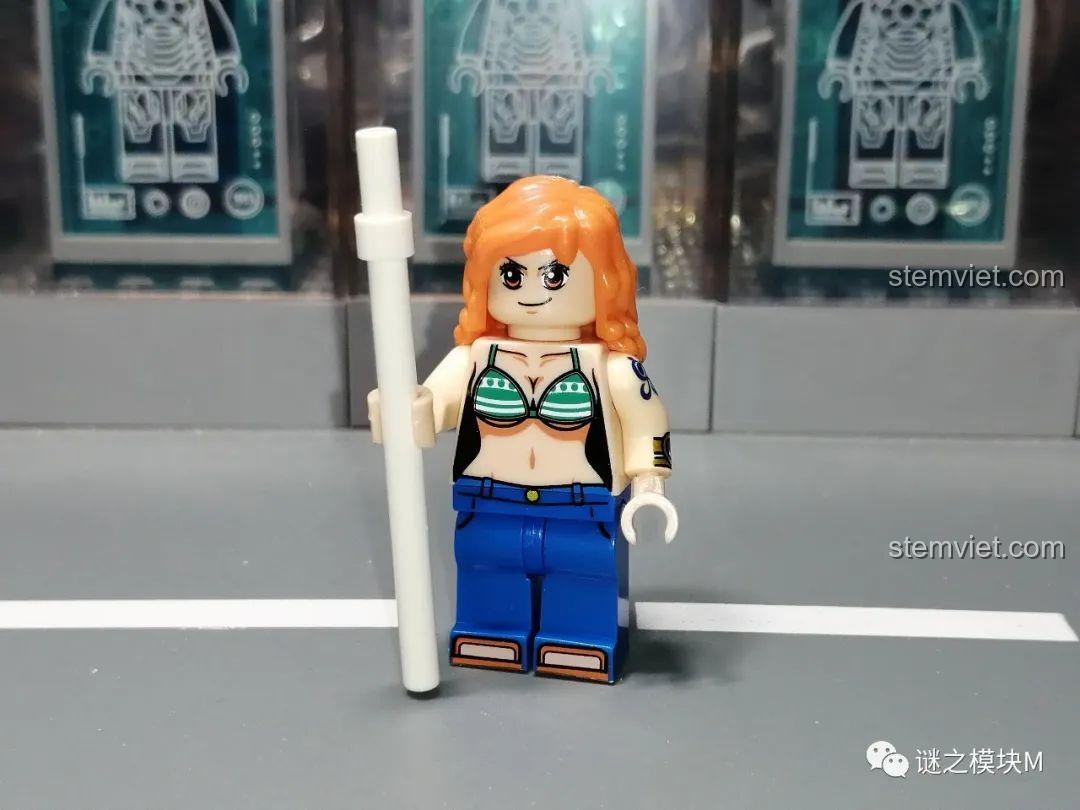 Minifigure hoa tiêu Nami trong bộ sưu tập One Piece, với mái tóc cam và cây gậy thời tiết.