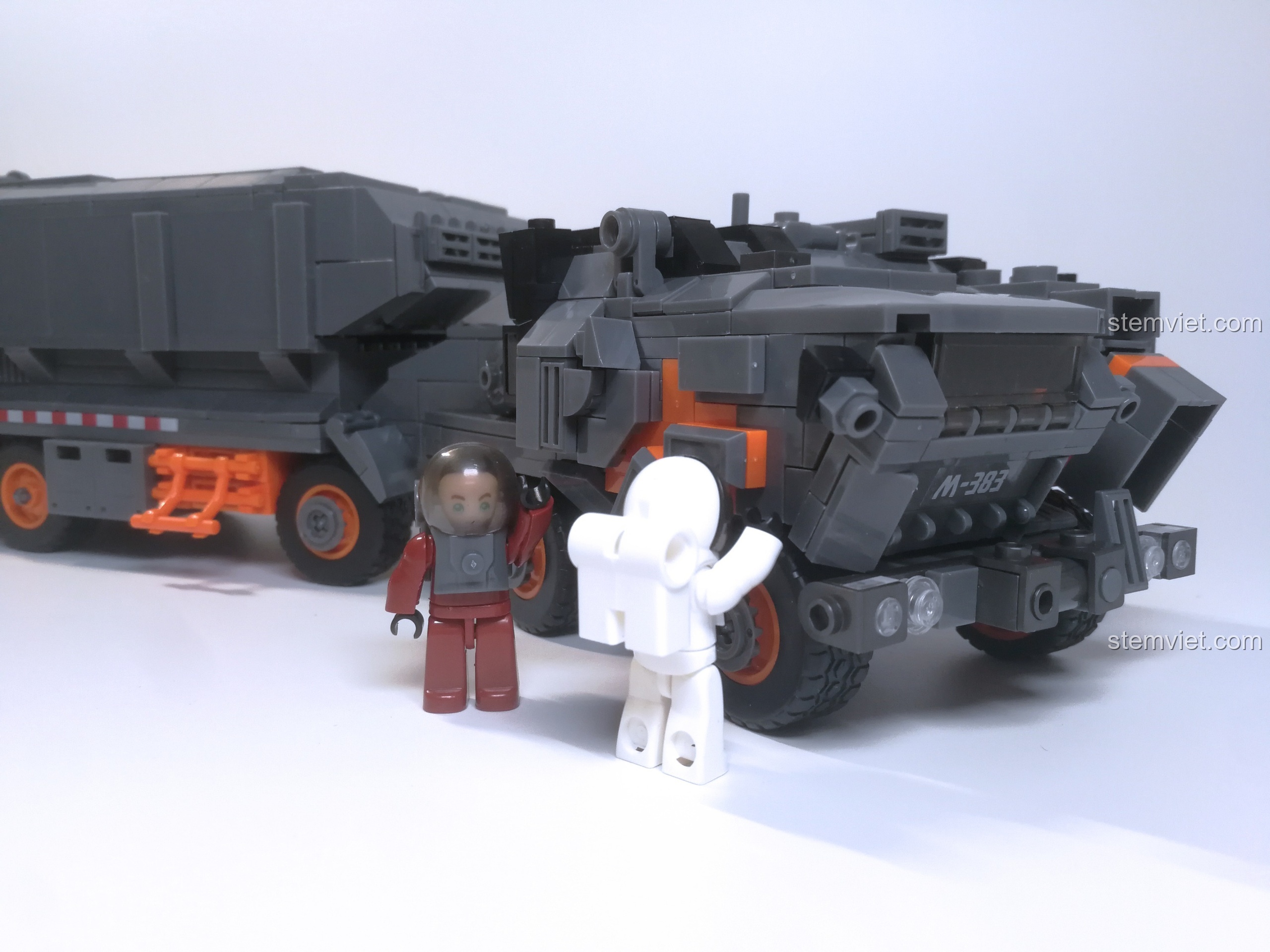 Hai nhân vật minifigure phi hành gia đi kèm bộ lắp ráp Xe Tải Chở Hàng Tận Thế M38-B0787 đang đứng cạnh xe tải.