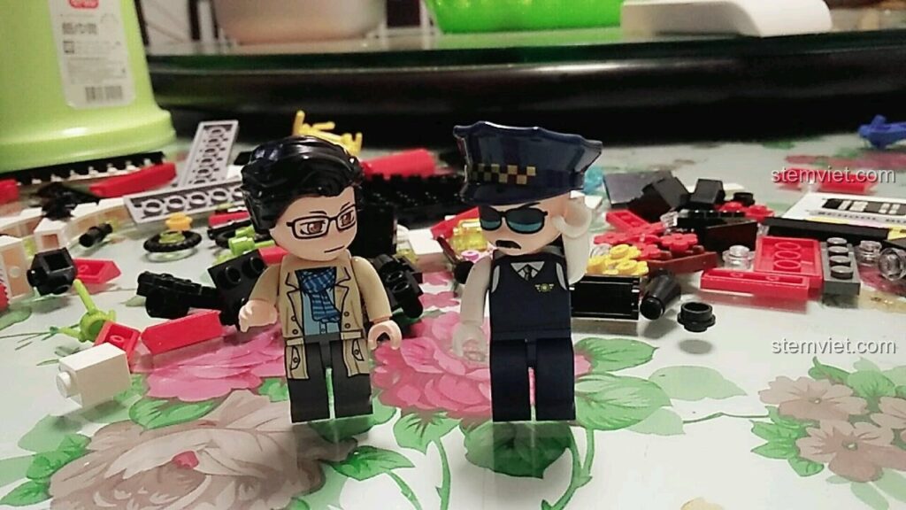 Hai minifigures cô giáo và bác tài xế trong bộ lắp ghép QMAN 1136 Xe Buýt Trường Học và Trạm Chờ, sẵn sàng bắt đầu công việc.