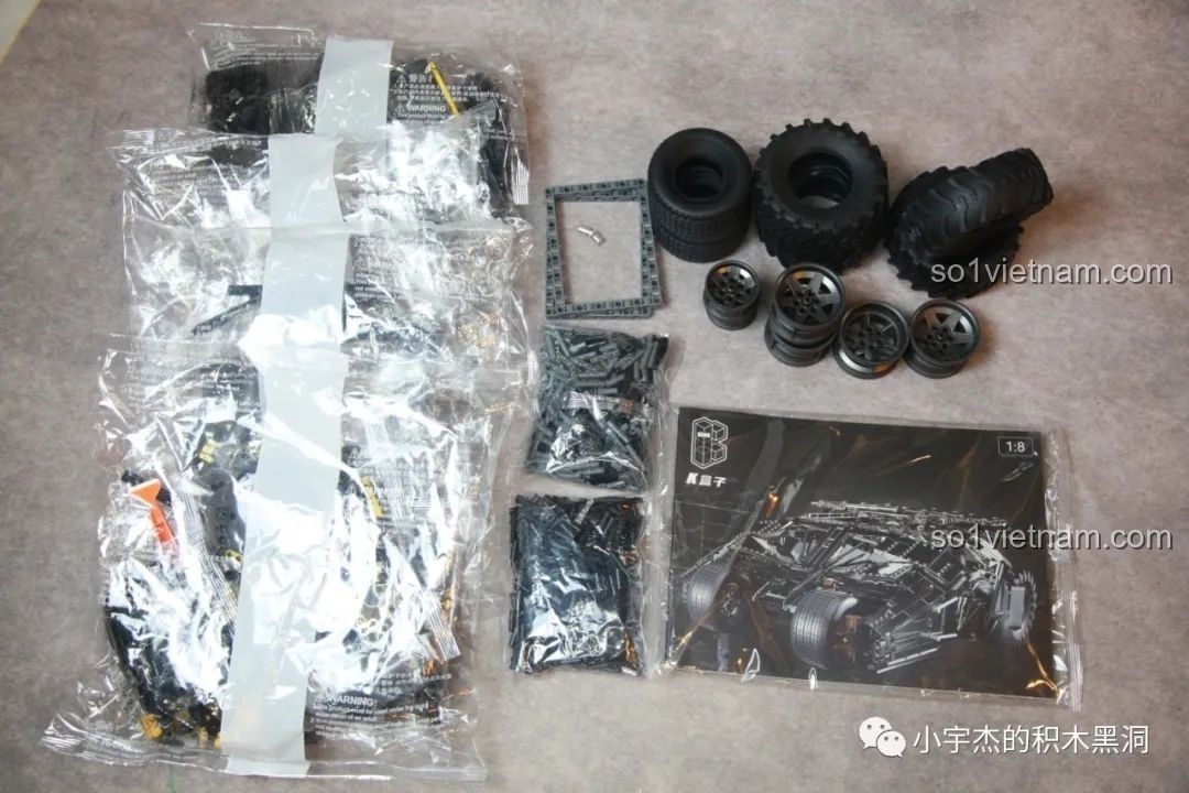 Toàn bộ linh kiện của bộ xếp hình K-Box 10517 Xe Batman Rambom sau khi mở hộp, bao gồm các túi mảnh ghép, lốp xe, và sách hướng dẫn lắp ráp.