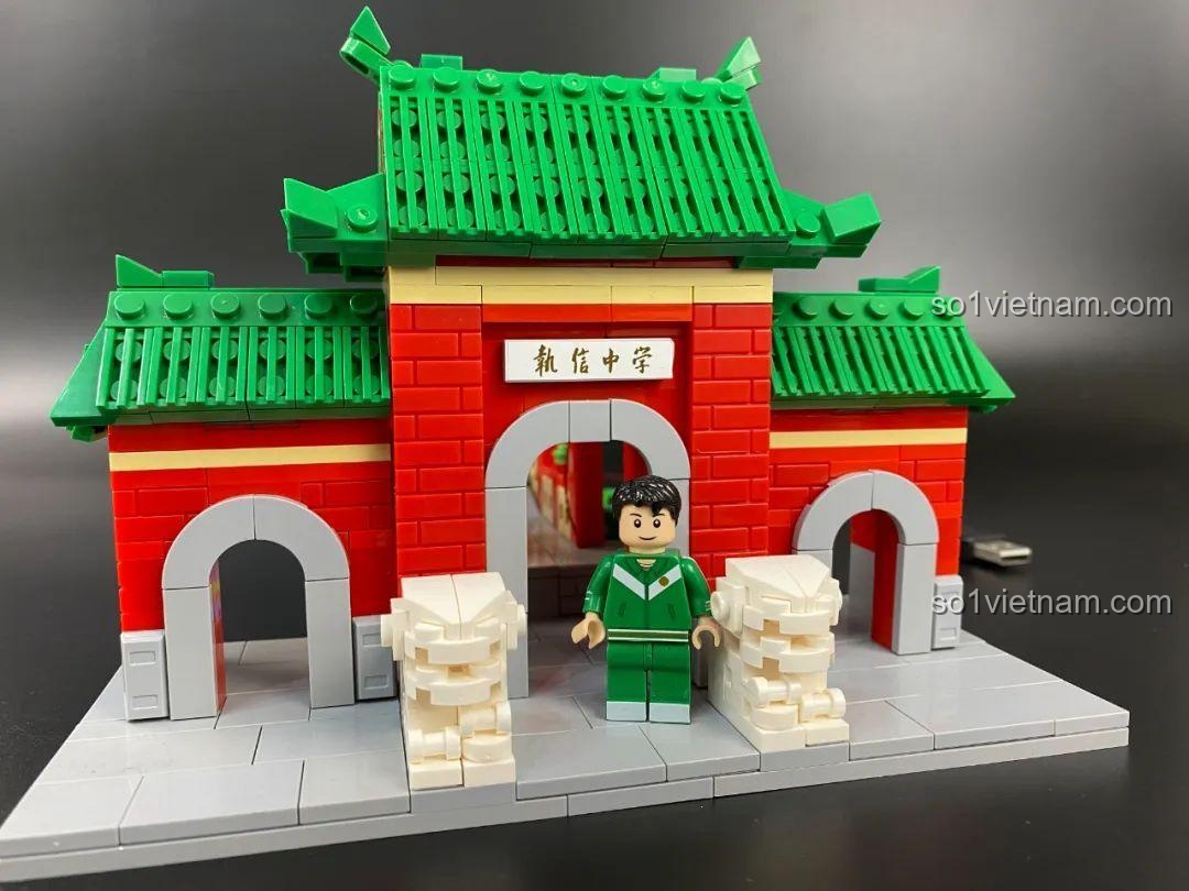 Minifigure học sinh Trung học Chiêu Tấn đứng cạnh mô hình cổng trường