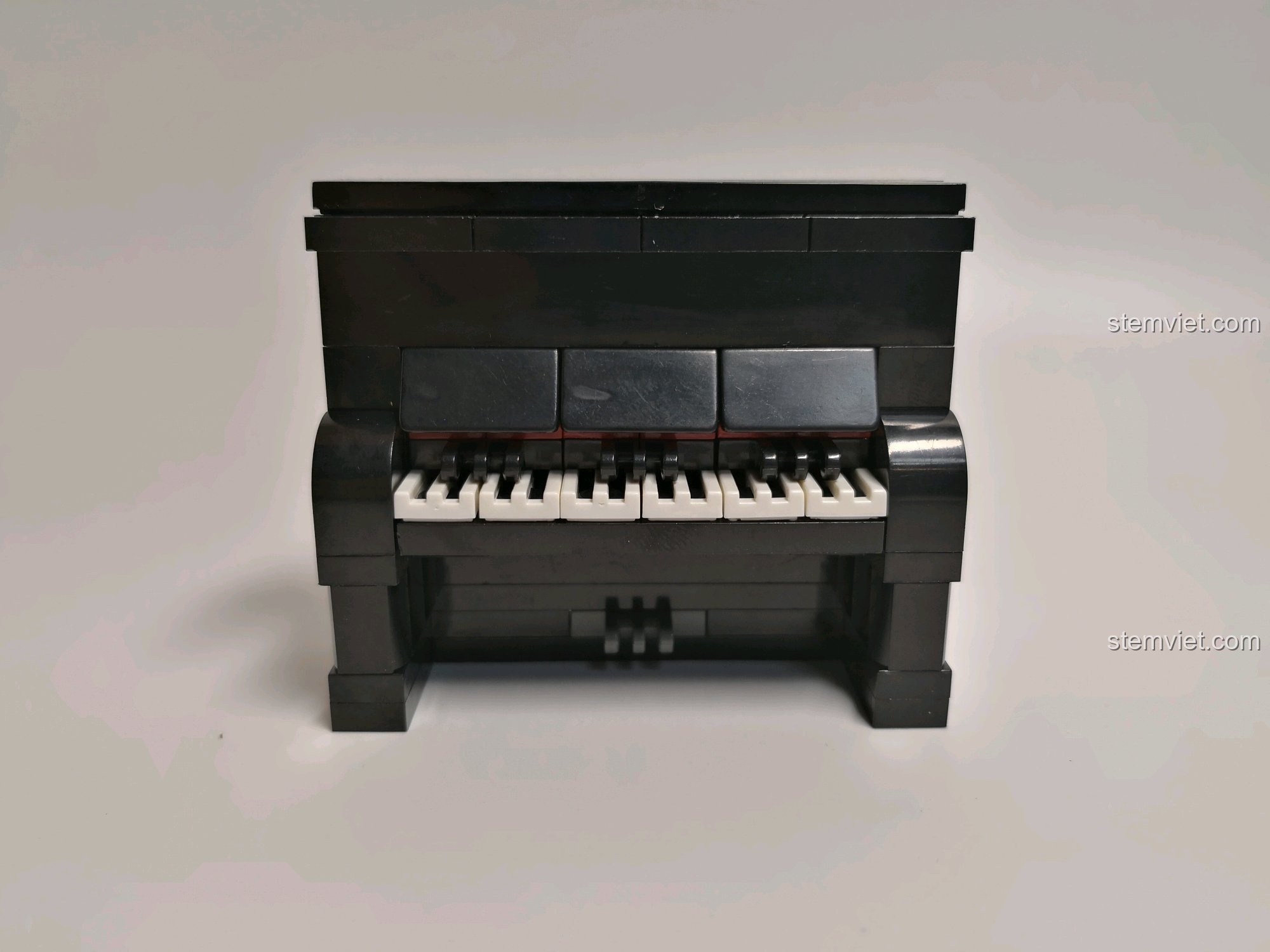 Mô hình cây đàn piano được lắp ráp hoàn chỉnh, với các phím đàn đen trắng chi tiết, là điểm nhấn của phòng thu âm nhạc.