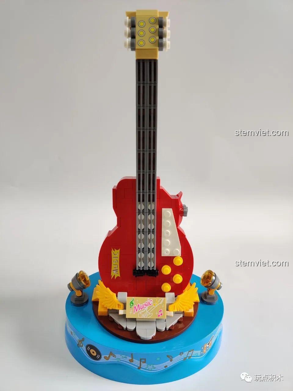 Mô hình Hộp Nhạc Guitar Điện WOMA C0365 hoàn thiện với cây đàn đỏ, sân khấu xanh và các chi tiết đèn chiếu.