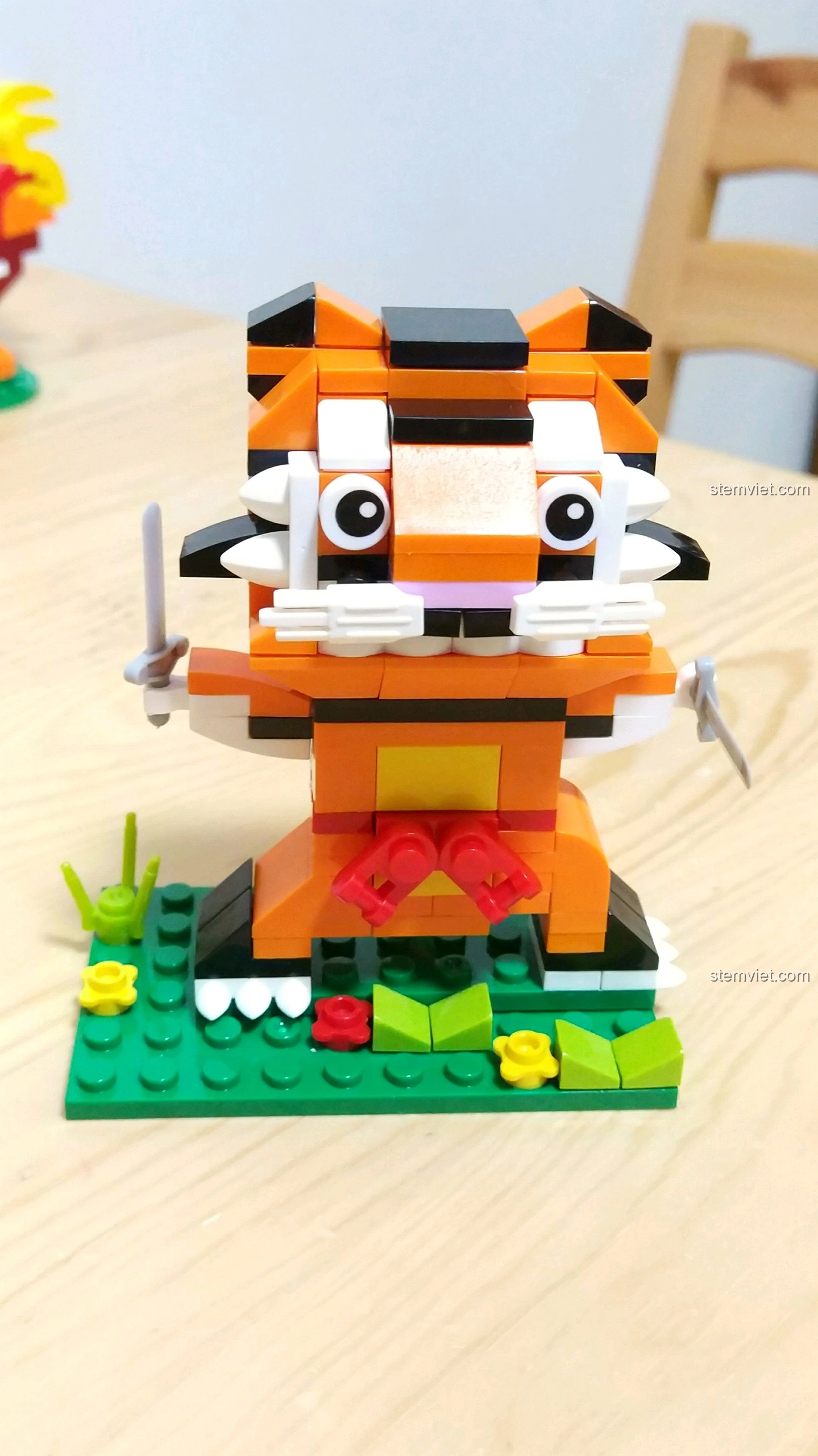 Mô hình Hổ Dần màu cam đen, cầm hai thanh kiếm nhỏ, đứng trên nền cỏ xanh, từ bộ lắp ráp 12 Con Giáp XINGBAO XB-18001.