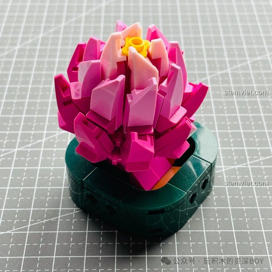 Mô hình hoa sen đá JAKI JK2727 đã hoàn thành, đặt trong chậu màu xanh đậm, với nhụy hoa vàng nổi bật.