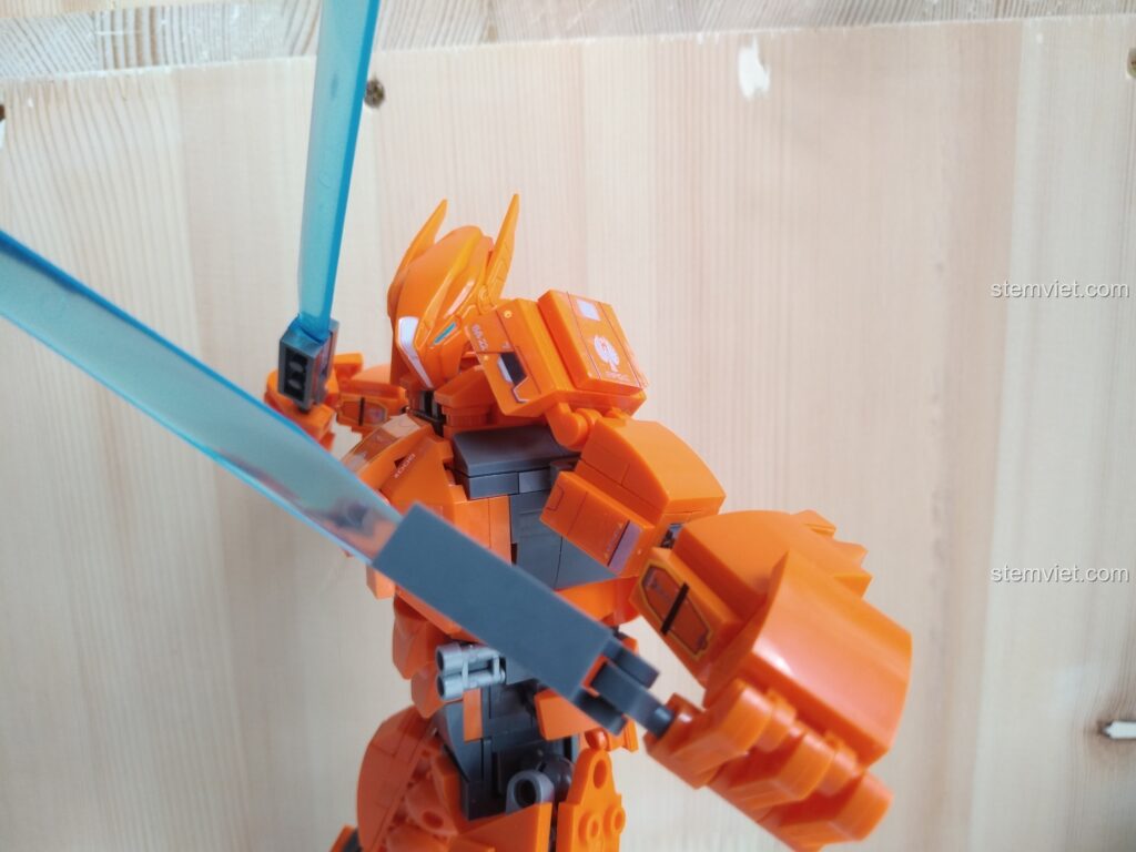 Cận cảnh mô hình Robot Jaeger Saber Athena M38-B0726B màu cam sau khi lắp ráp hoàn chỉnh, đang cầm hai thanh kiếm ánh sáng màu xanh.