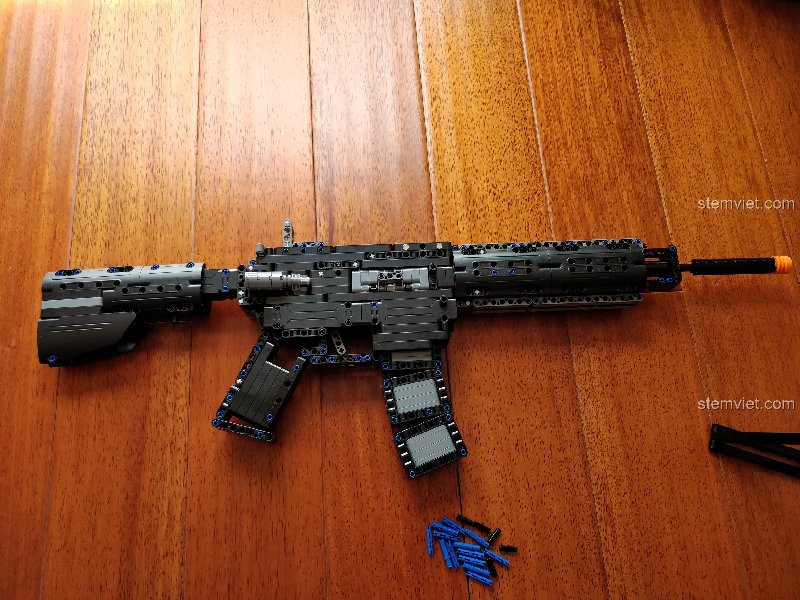 Mô hình Súng M4A1 CaDA C81005 hoàn thiện, trưng bày trên sàn gỗ, cho thấy các chi tiết và tỉ lệ 1:1 ấn tượng.