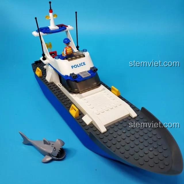 Mô hình tàu cảnh sát tuần tra Sluban B0657 đã hoàn thiện với minifigure thuyền trưởng, bên cạnh là một con cá mập.