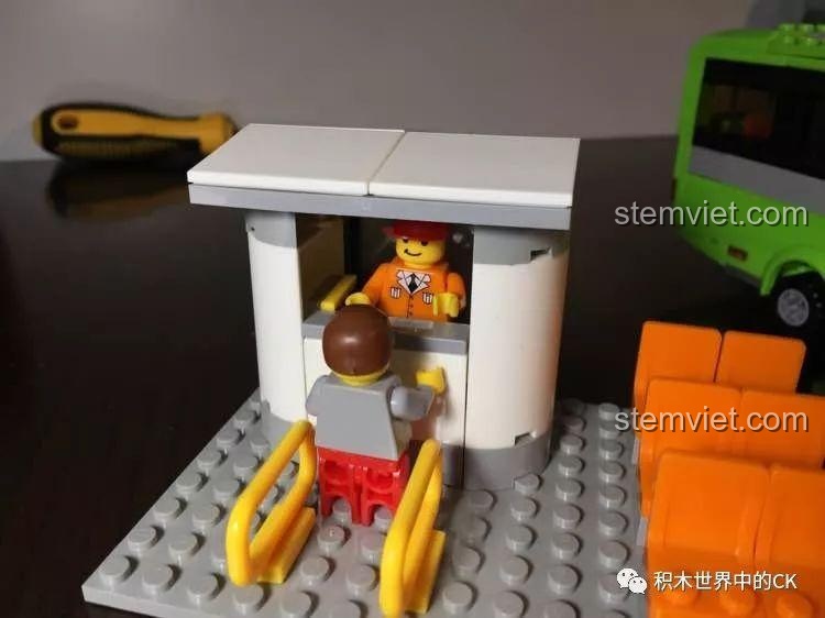 Hành khách đang mua vé tại quầy bán vé của trạm chờ trong bộ đồ chơi Trạm chờ xe buýt cho bé trai từ 6 tuổi.