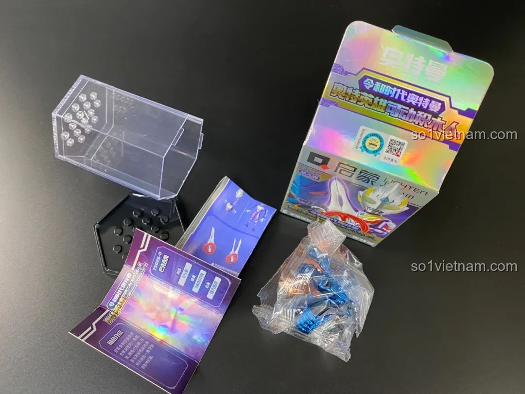 Mở một hộp blind box Ultraman Qman khác, bên trong là túi, thẻ bài, đế và hộp trưng bày.