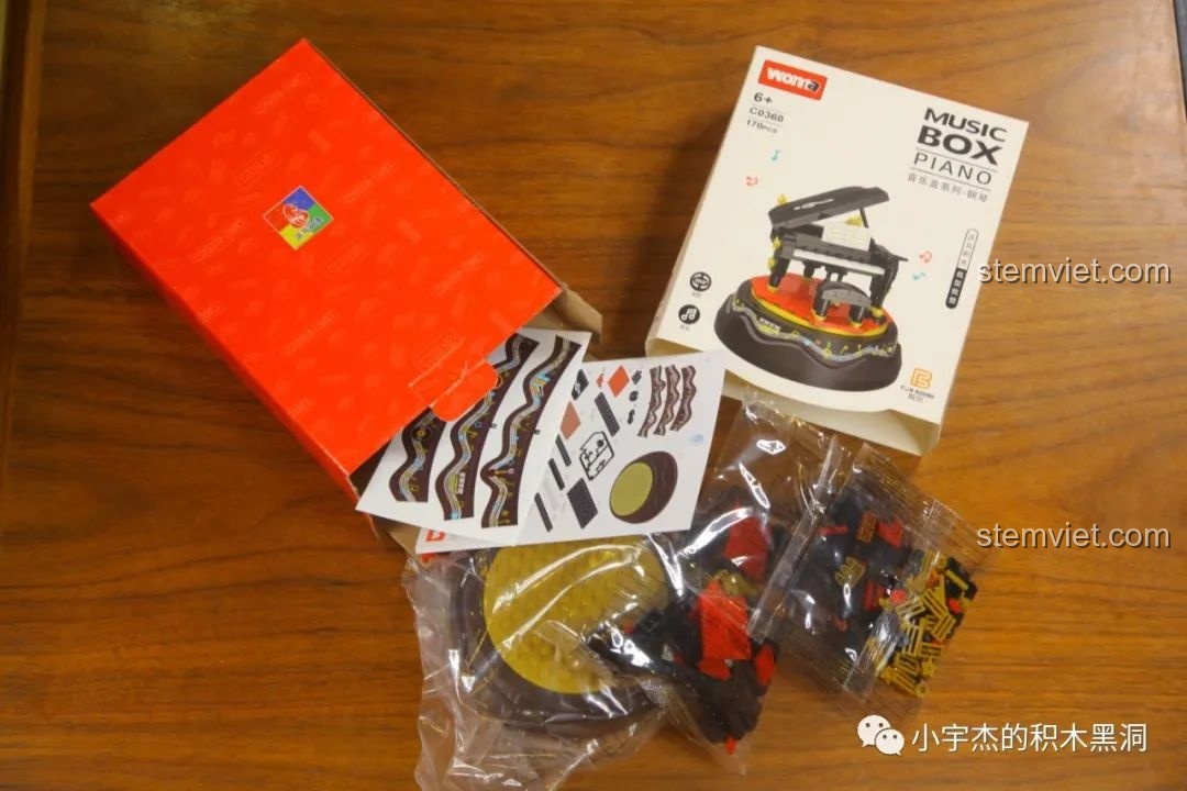 Mở hộp bộ lắp ráp hộp nhạc WOMA C0360 chủ đề đàn piano, với các túi mảnh ghép, sticker và sách hướng dẫn.