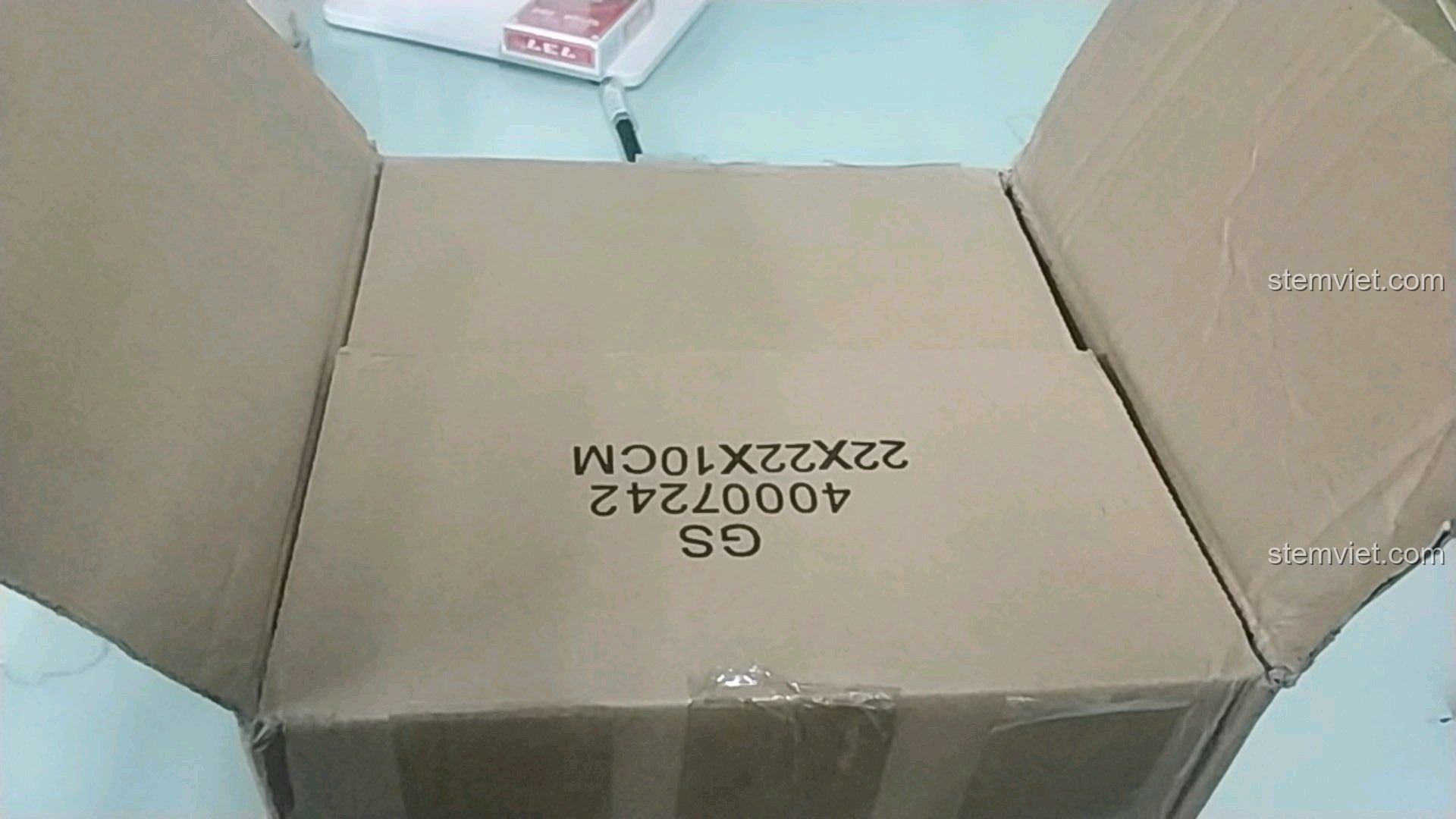 Mở thùng carton, để lộ hộp sản phẩm Mô hình toa tàu chủ đề Noel Enlighten 626 bên trong.