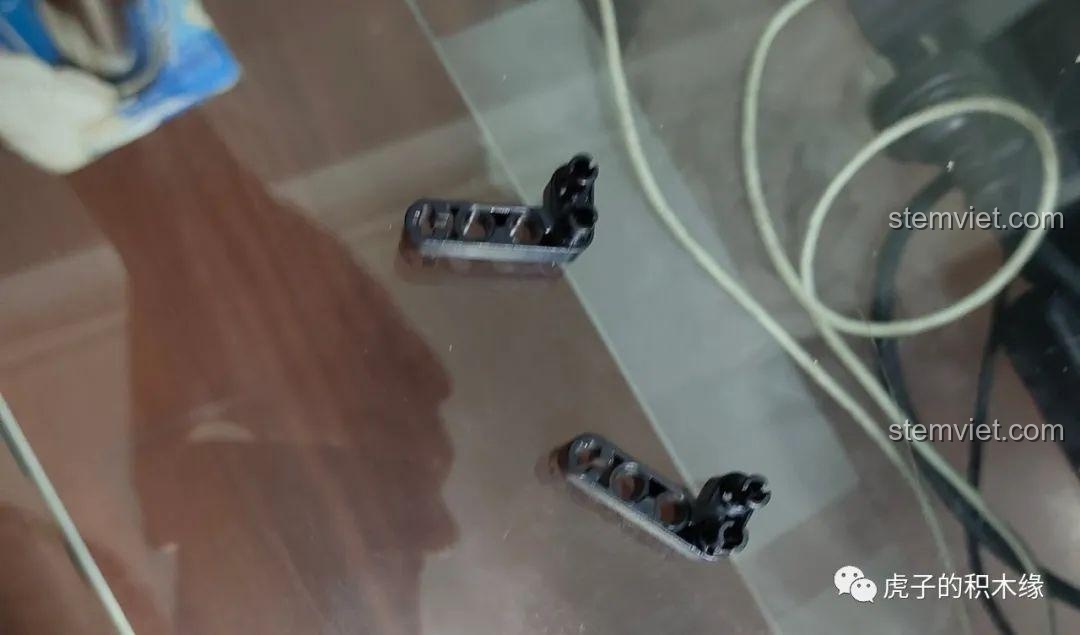 Các chi tiết Technic màu đen được tháo rời, chuẩn bị cho việc sửa đổi cản sau để lắp vừa bánh xe lớn hơn với bộ Phụ kiện motor hóa xe Jeep Wrangler 13124 D.