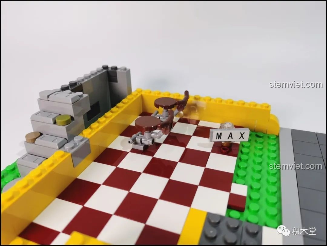 Lắp ráp nội thất tầng trệt của bộ Mould King 16031 Tiệm Cắt Tóc Phố Nhỏ, với sàn gạch caro và bàn ghế.