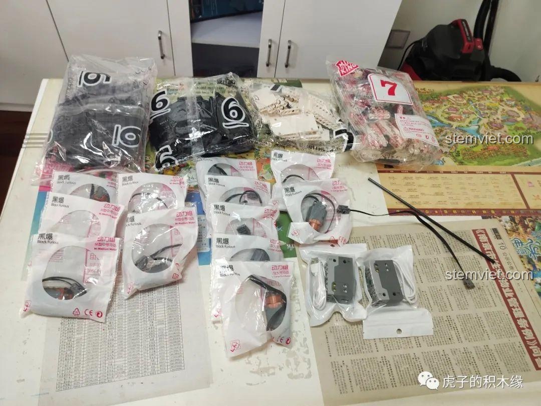 Nội dung hộp B của bộ đồ chơi Mould King 17002, chứa các động cơ, hộp pin và các túi chi tiết còn lại, sẵn sàng cho việc hoàn thiện mô hình cần cẩu bánh xích.