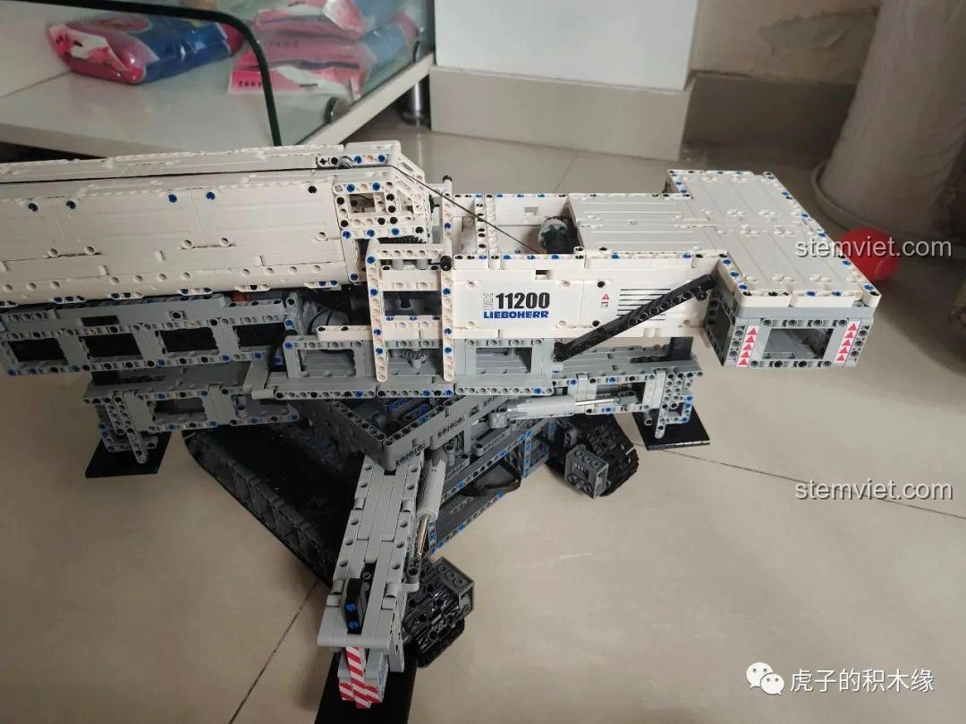 Mô hình cần cẩu bánh xích Mould King 17002 Liebherr LTR 11200 đã hoàn thiện, đặt trên sàn nhà, sẵn sàng hoạt động.