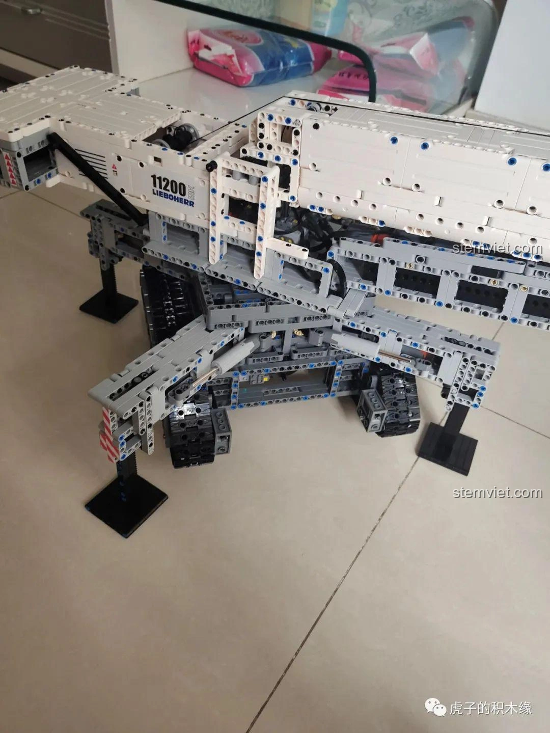 Mô hình cần cẩu bánh xích Mould King 17002 Liebherr LTR 11200 đã hoàn thiện, đặt trên sàn nhà, sẵn sàng hoạt động.