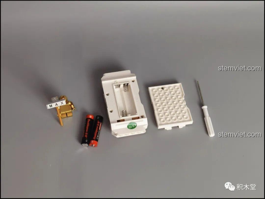 Điều khiển từ xa của Mould King 18026 cùng với tuốc nơ vít nhỏ và pin AAA, sẵn sàng cho việc điều khiển xe.