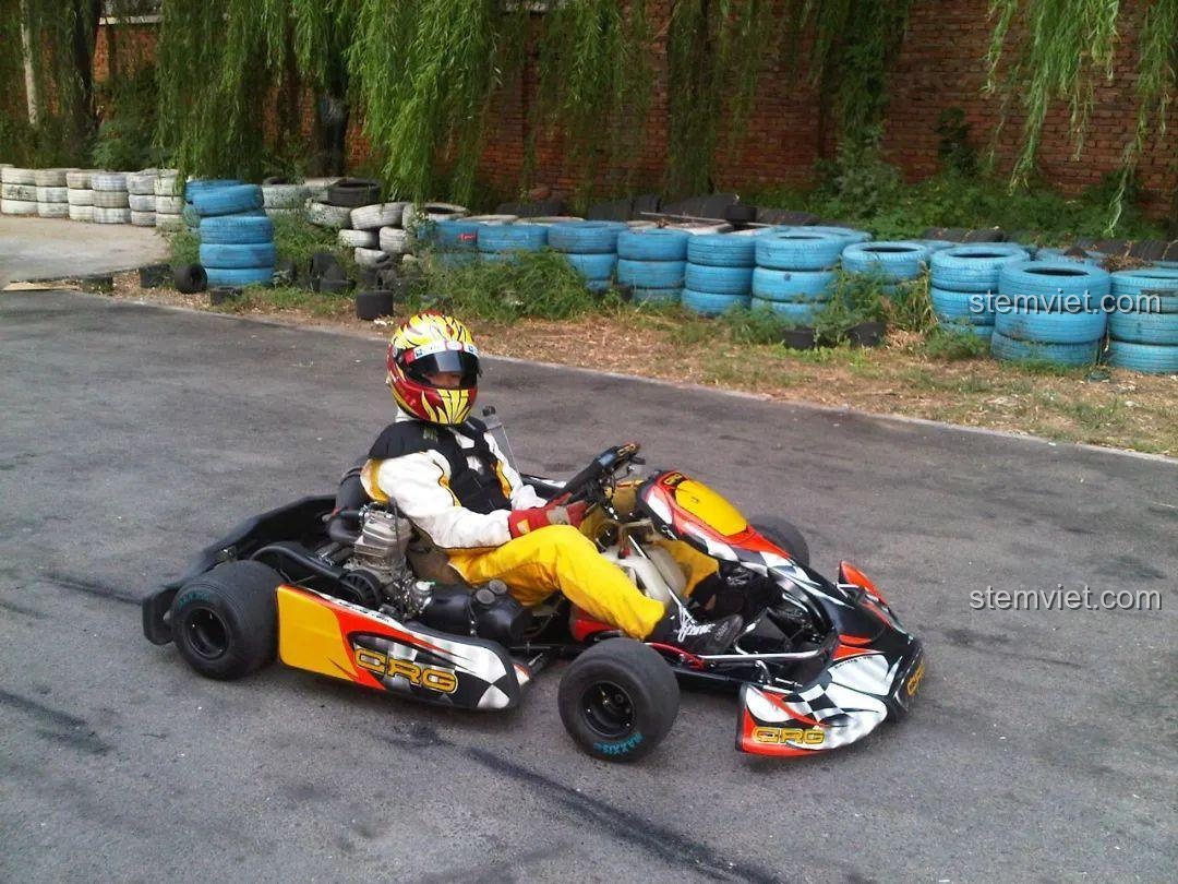 Hình ảnh một tay đua chuyên nghiệp ngồi trên chiếc xe kart thật tại đường đua, thể hiện sự chân thực của môn thể thao này.