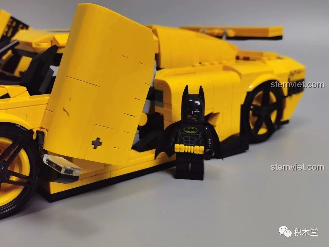 Người máy cầm vũ khí bên cạnh mô hình Lego Koenigsegg Regera màu vàng.