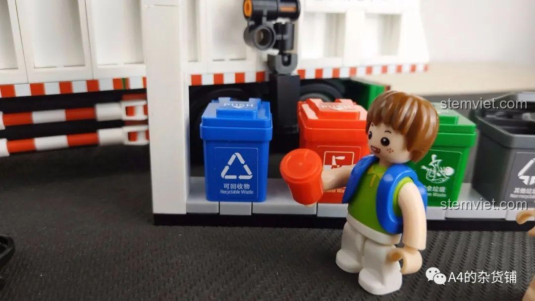 Cận cảnh nhân vật em bé trai đang chơi với thùng rác trong bộ đồ chơi Sluban B0780.