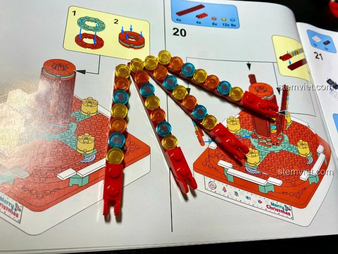 Quá trình lắp ráp các dải trang trí đầy màu sắc xung quanh trục xoay của Hộp nhạc Giáng Sinh Xoay Tự Động JAKI JK1365. Đồ chơi lắp ráp Giáng Sinh có nhạc.