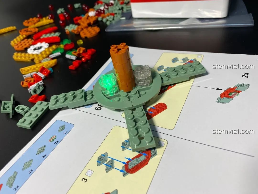 Lắp đặt viên gạch phát sáng vào vị trí trung tâm của Hộp nhạc Giáng Sinh Xoay Tự Động JAKI JK1365. Đồ chơi lắp ráp Giáng Sinh có nhạc.