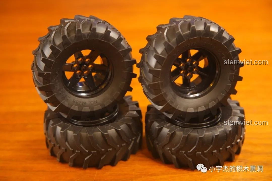 Bốn bánh xe lớn với lốp gai hầm hố của mô hình Mould King 18006 Xe Tải Kéo Nổi Loạn Hậu Tận Thế, sẵn sàng chinh phục địa hình.