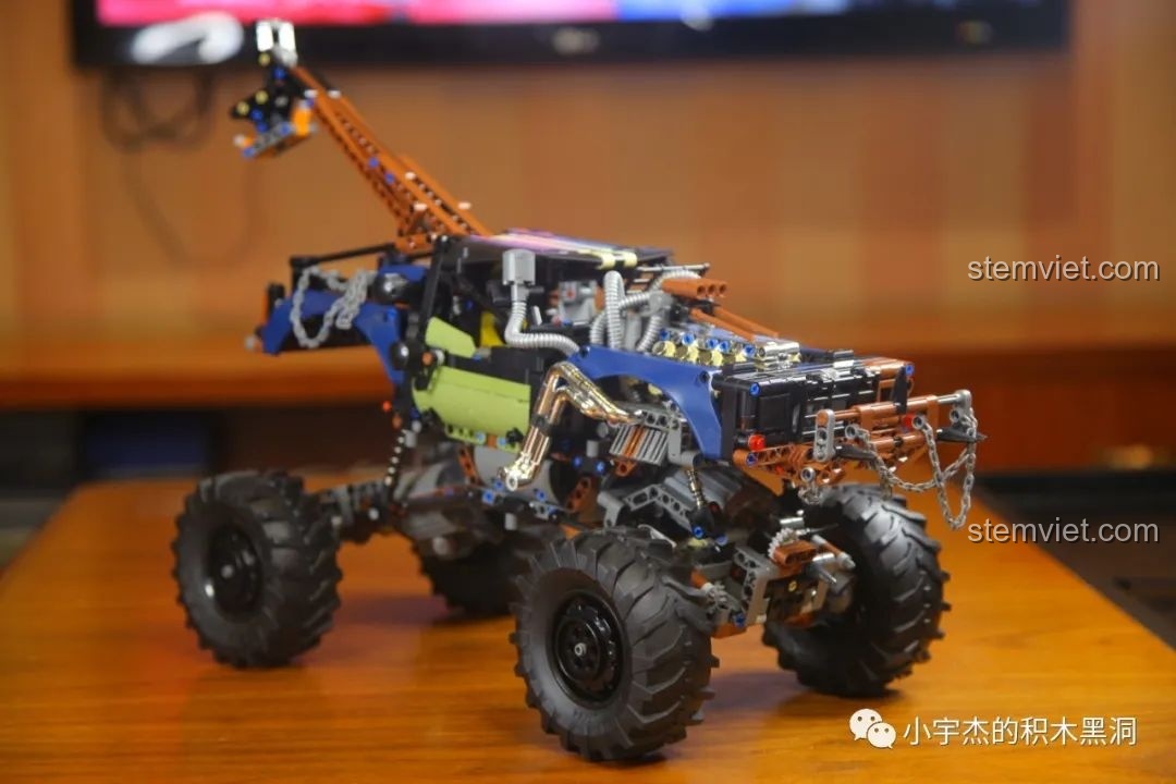 Mô hình Mould King 18006 Xe Tải Kéo Nổi Loạn Hậu Tận Thế trên giá đỡ, thể hiện hệ thống treo và khoảng sáng gầm.