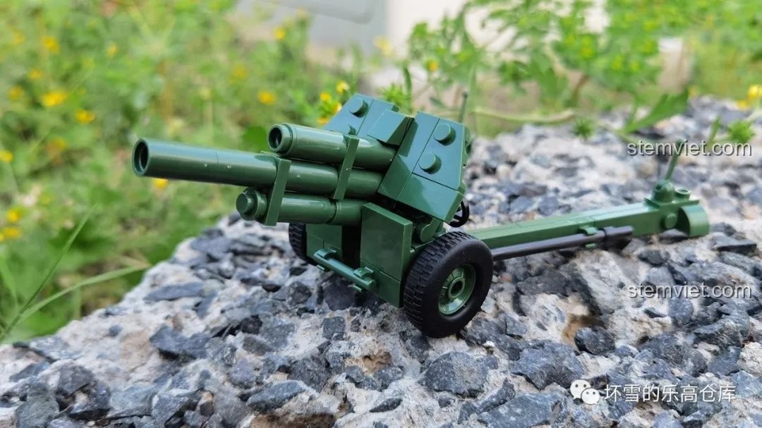 Mô hình pháo M-30 QUANGUAN 122mm đặt trên nền đá sỏi, thể hiện chi tiết và màu sắc xanh quân đội. Nhận xét QUANGUAN 100078 Pháo cao xạ.