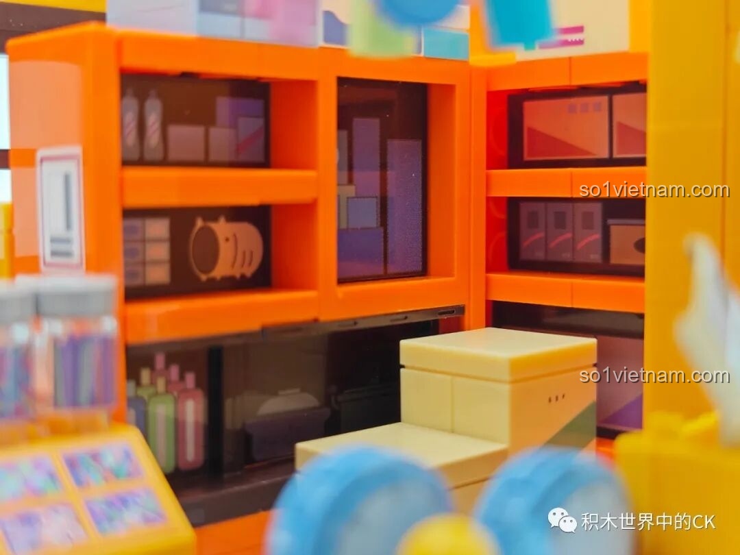 Nội thất bên trong Tiệm Tạp Hóa Maruko Wekki, bao gồm các kệ hàng màu cam và các hộp đồ.