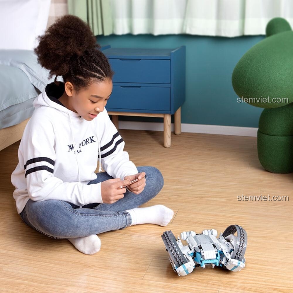 Một bé gái đang điều khiển đồ chơi robot ONEBOT OBFV05AIQI bằng điện thoại, thể hiện tính năng kết nối thông minh của sản phẩm.