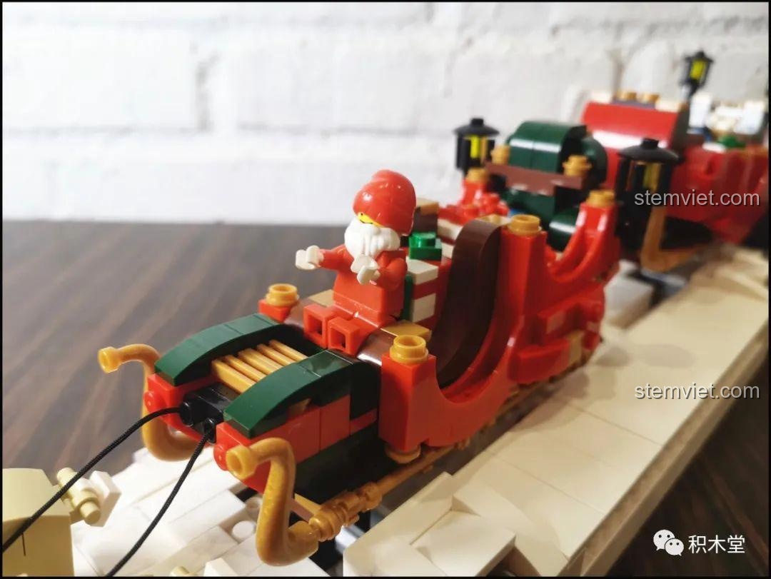 Cận cảnh Ông già Noel đang ngồi trên cỗ xe trượt tuyết, tay cầm dây cương điều khiển đoàn tuần lộc.