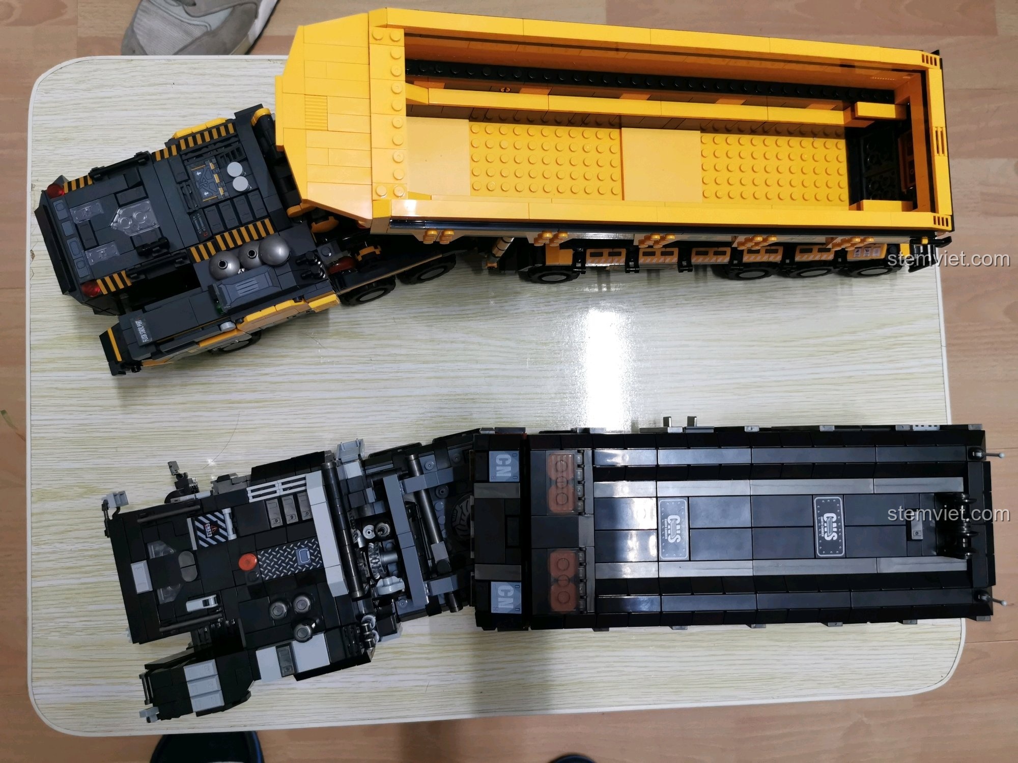 So sánh hai mẫu xe tải, một chiếc màu đen và vàng, một chiếc màu xám và vàng.