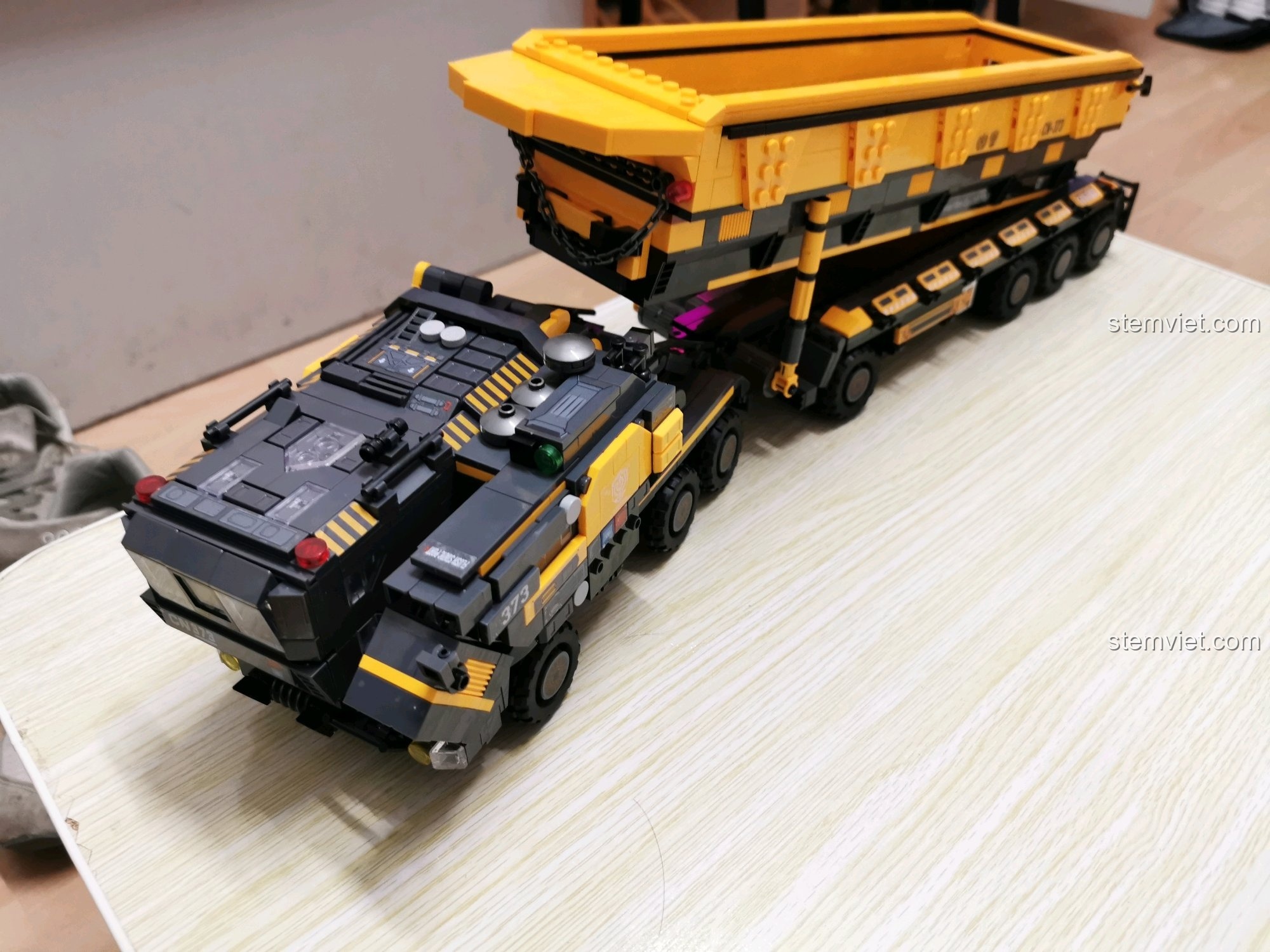 Toàn cảnh bộ xe tải vận chuyển CN373 màu đen và vàng, bao gồm đầu kéo và thùng xe.