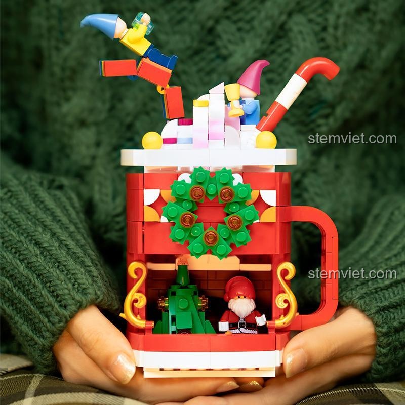 Mô hình cốc đồ uống Giáng Sinh Pantasy 25001 được cầm trên tay, thể hiện kích thước thực tế và sự ấm áp của sản phẩm, phù hợp làm đồ chơi trang trí cho mùa Giáng Sinh.