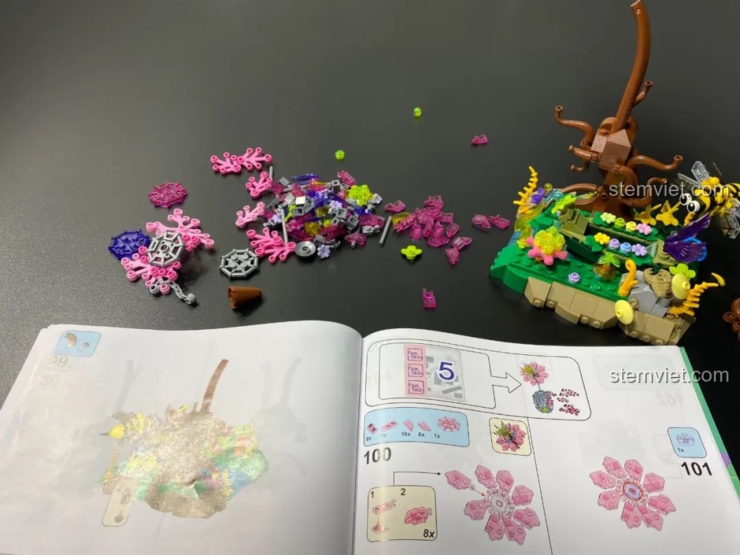 Các mảnh ghép trong suốt màu hồng và tím của túi số 5 và cuốn hướng dẫn lắp ráp Pantasy 15002, chuẩn bị cho việc xây dựng bông hoa và lồng.