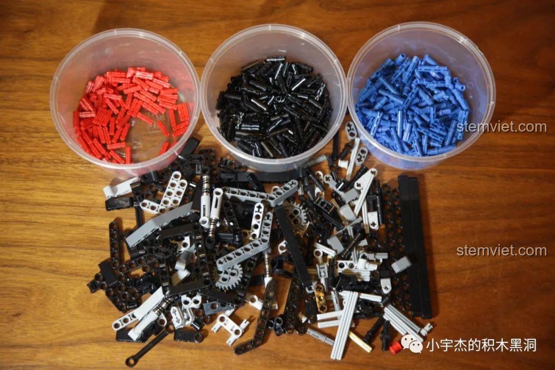 Các chi tiết từ túi số 1 được đổ ra khay, bao gồm các chốt màu đỏ, xanh, đen và các bộ phận khung gầm.